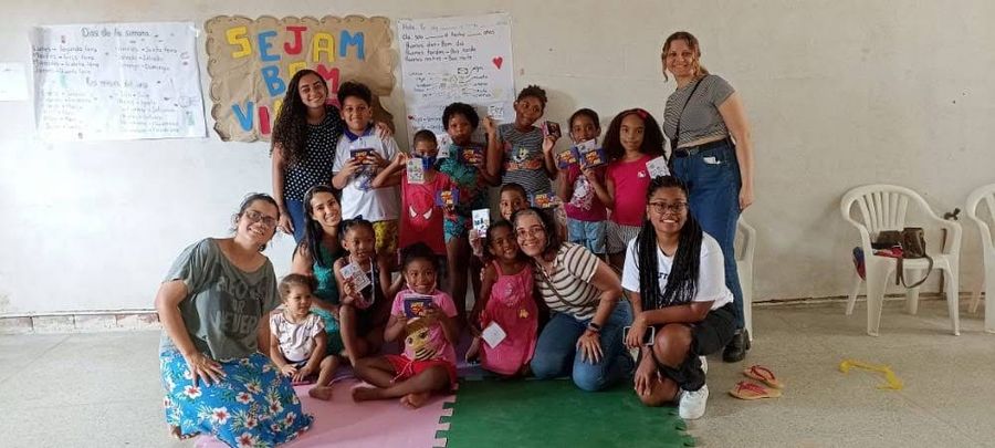 Voluntários e crianças reunidos em atividade da Usina da Vida, com um cartaz de boas-vindas ao fundo