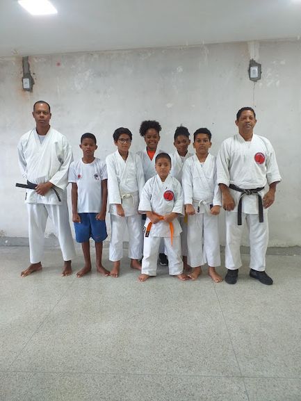 Crianças e instrutores de karatê uniformizados, em fila